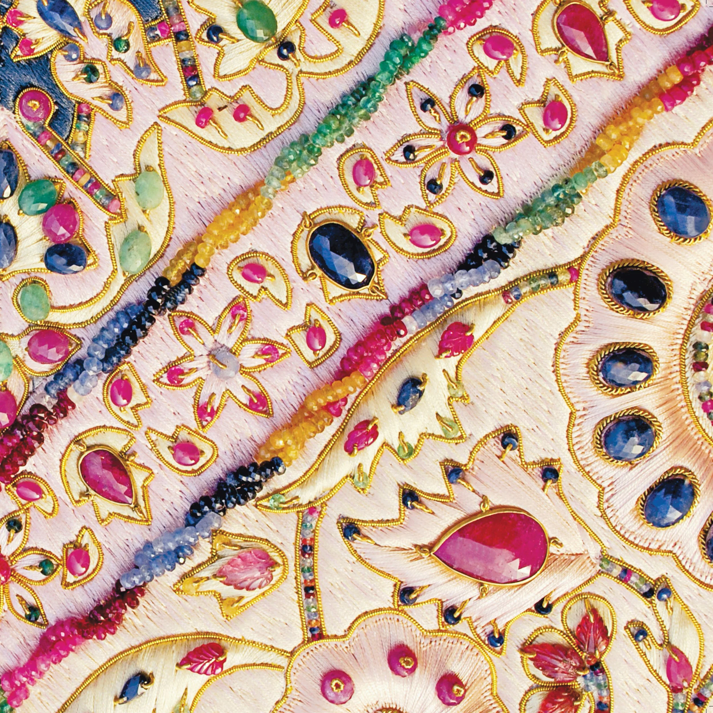 Close-up of colorful, ornate embroidery with beads and gemstones, featuring floral patterns on fabric.
