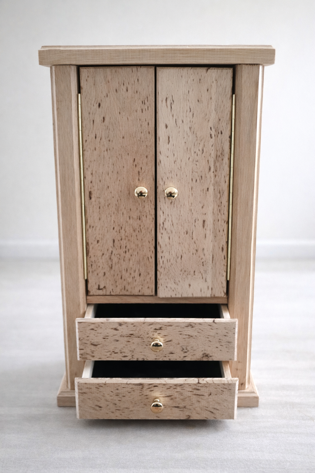 Small wooden cabinet with two doors on top and three drawers below, set against a plain white wall.