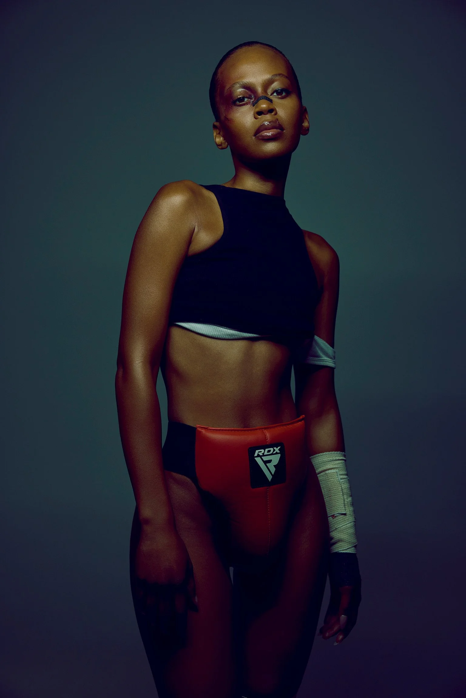 A woman athletes in a dark tank top and red athletic gear, standing against a plain background.
