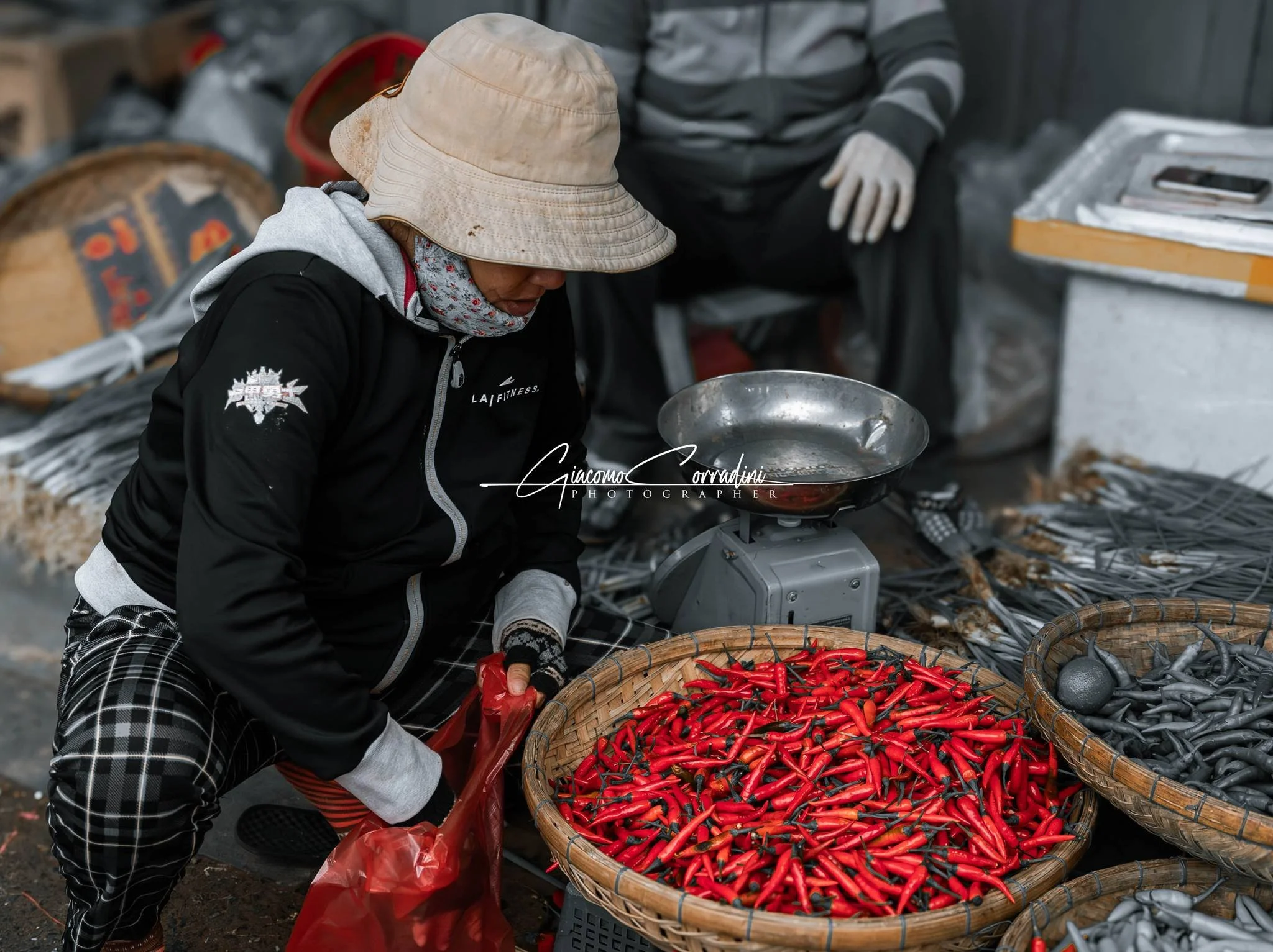 Venditore seleziona peperoncini rossi in un cesto di vimini, Hanoi Vietnam Wild Travel Films