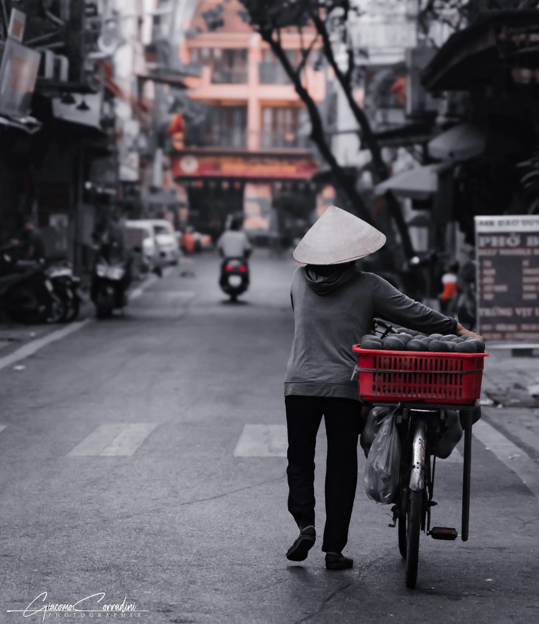 Donna con cappello conico spinge una bicicletta per strada, Hanoi Vietnam Wild Travel Films