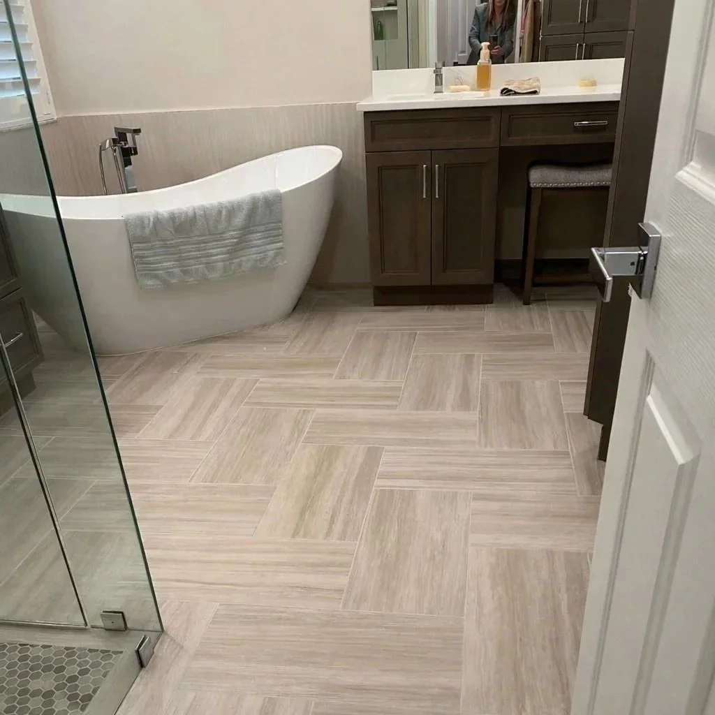 The warm beige tile flooring installed in a herringbone pattern adds texture and depth to the serenity feel of this primary bathroom retreat.