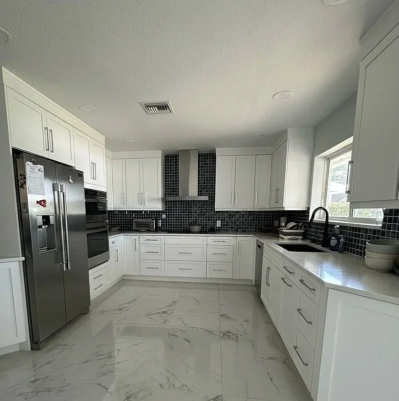 AFTER: Swapped the heavy brown tones for crisp white shaker cabinets to give the room an upgraded polished feel while making the entire footprint feel twice as grand.