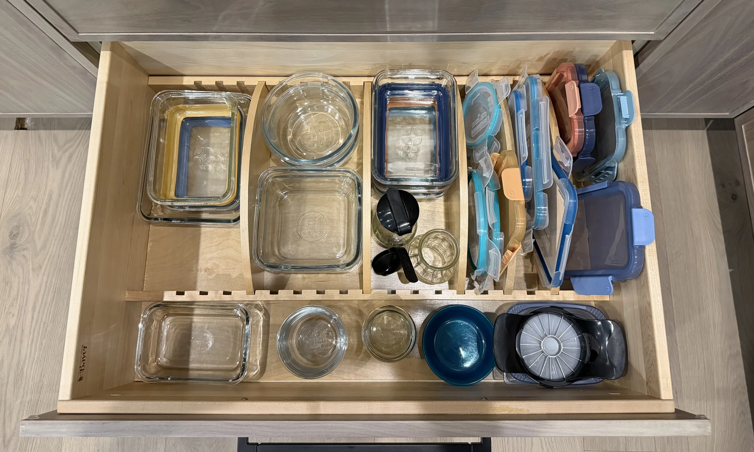 Deep drawers with adjustable inserts provide dedicated, visible storage for food containers and lids.