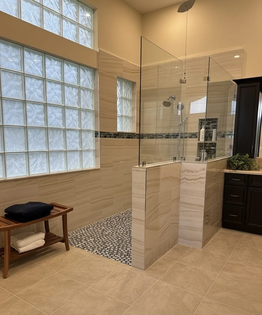 This contemporary bathroom blends warm neutrals with clean lines to create a calm, restorative atmosphere. Every element was selected with health and safety in mind. Natural light, rich wood cabinetry, and simple furnishings complete its modern, invi