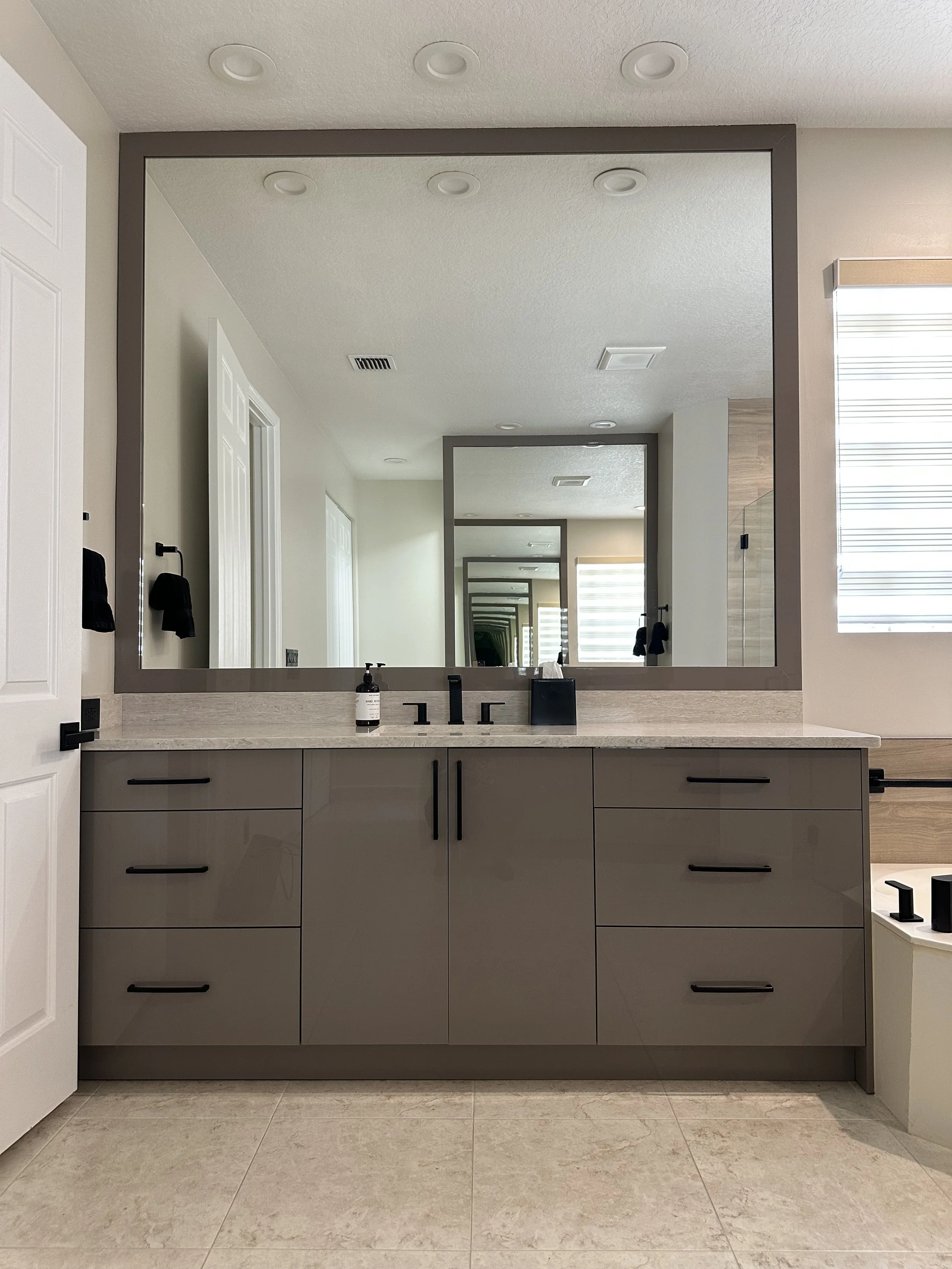 This sleek vanity area showcases cabinetry in a Basalto High Gloss finish with a custom matching mirror surround. The materials selected shape the sophisticated, modern aesthetic.