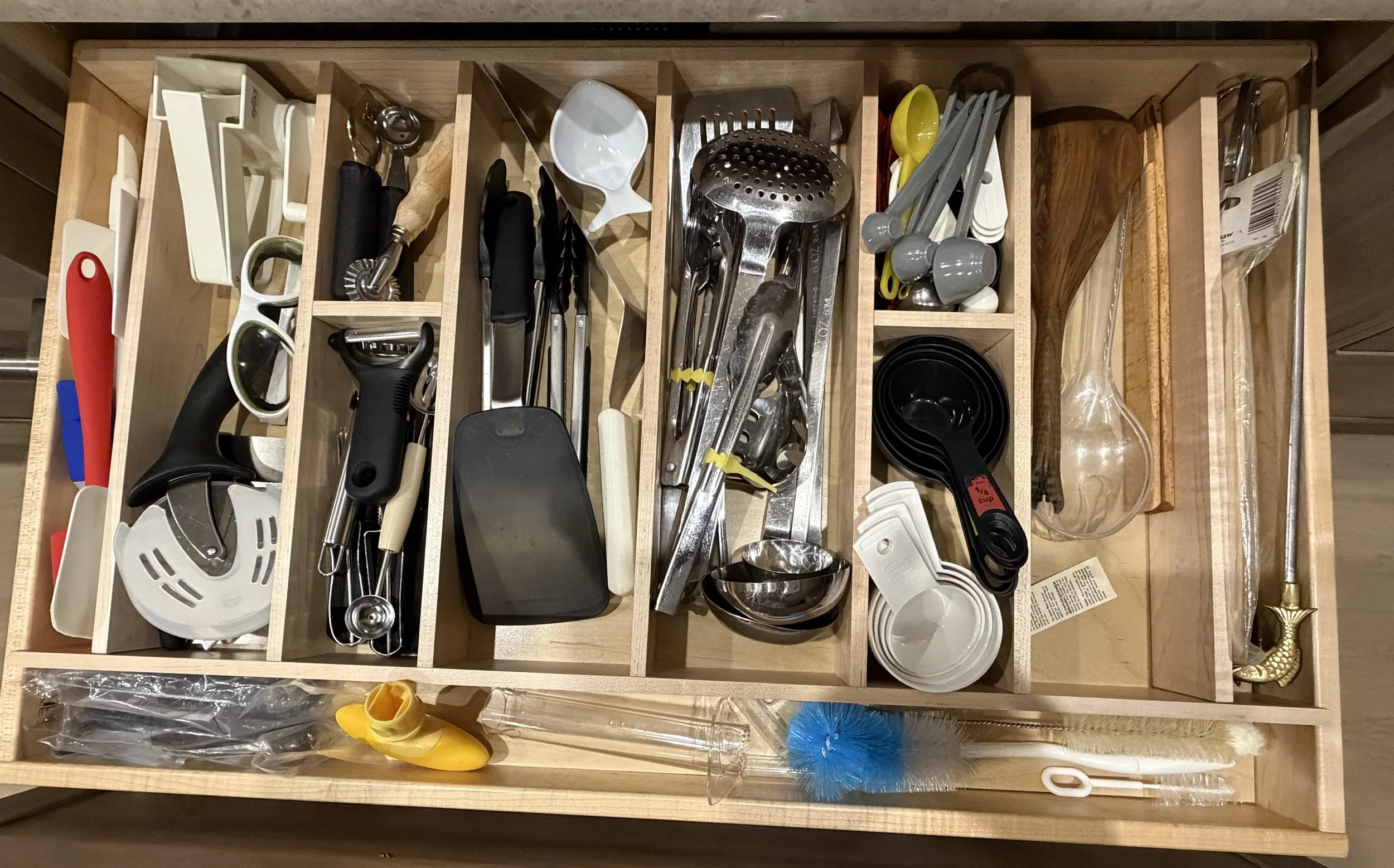 Wooded utensil drawer insert keeps cooing utensils, measuring tools and everyday gadgets neatly sorted and within easy reach.