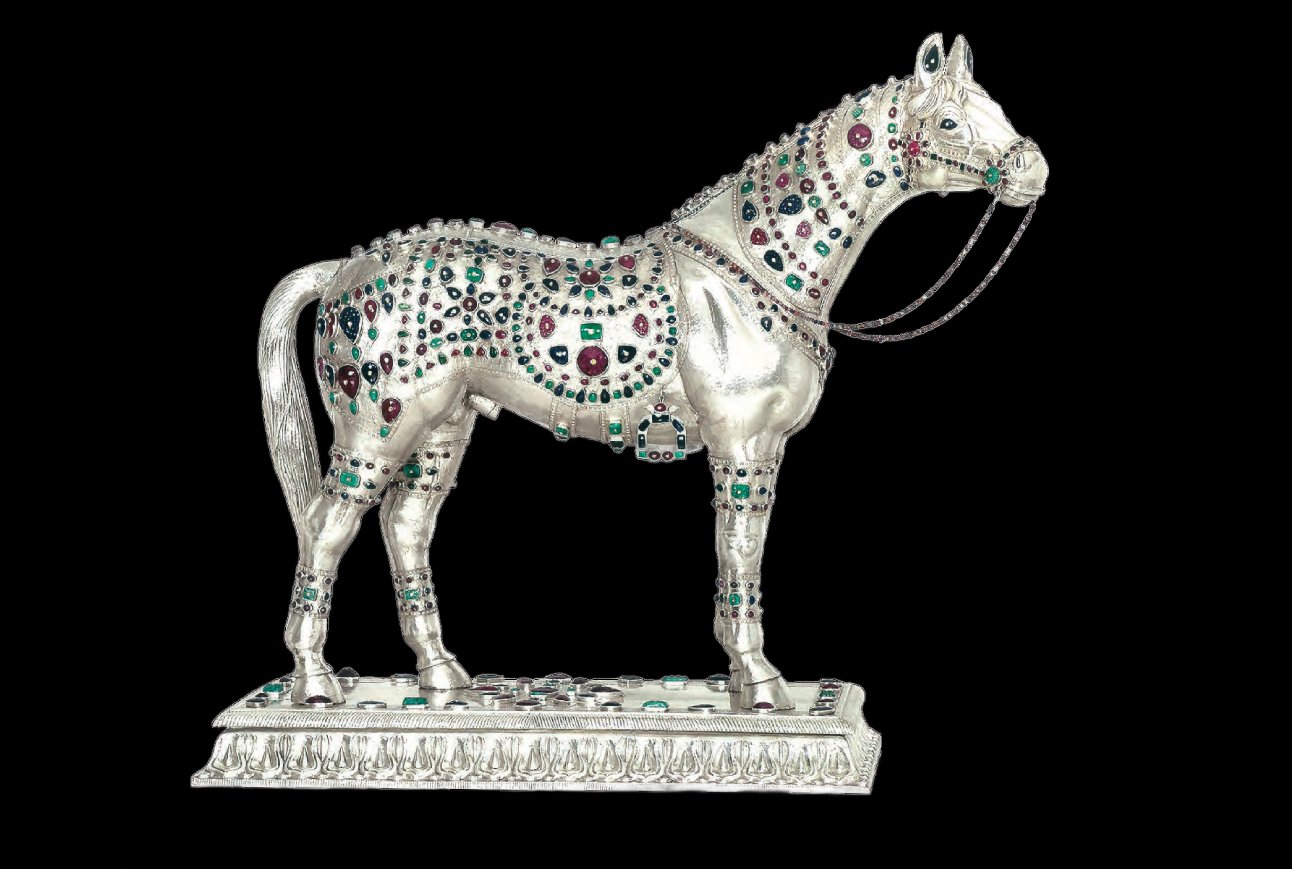 Decorative silver horse figurine adorned with multicolored gemstones on a black background.