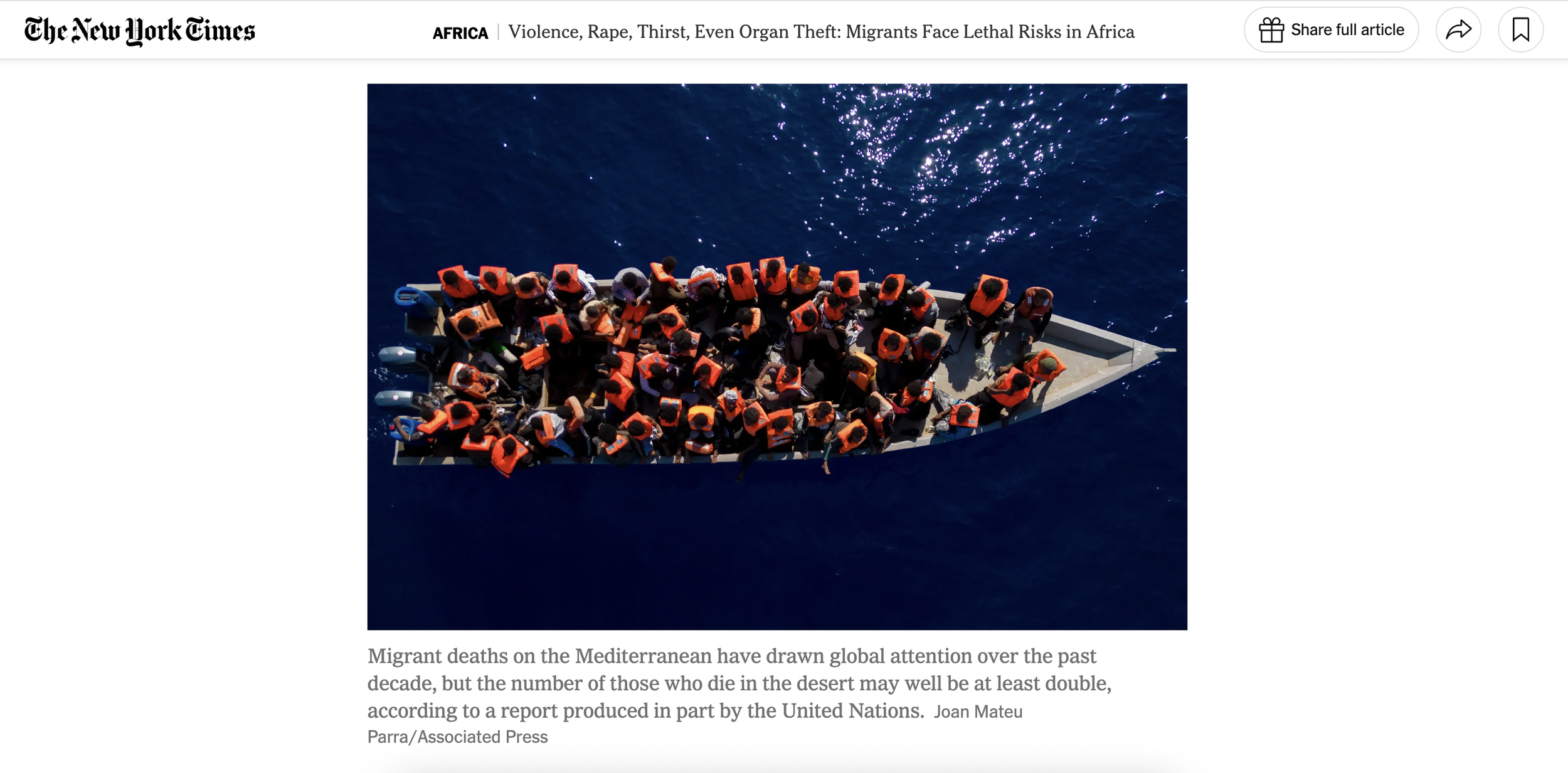 Aerial view of a boat carrying numerous migrants wearing orange life jackets on dark blue water