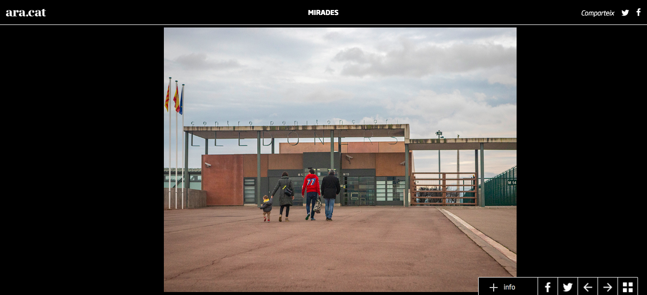 People walking toward a modern building with flags on the left and a cloudy sky above.