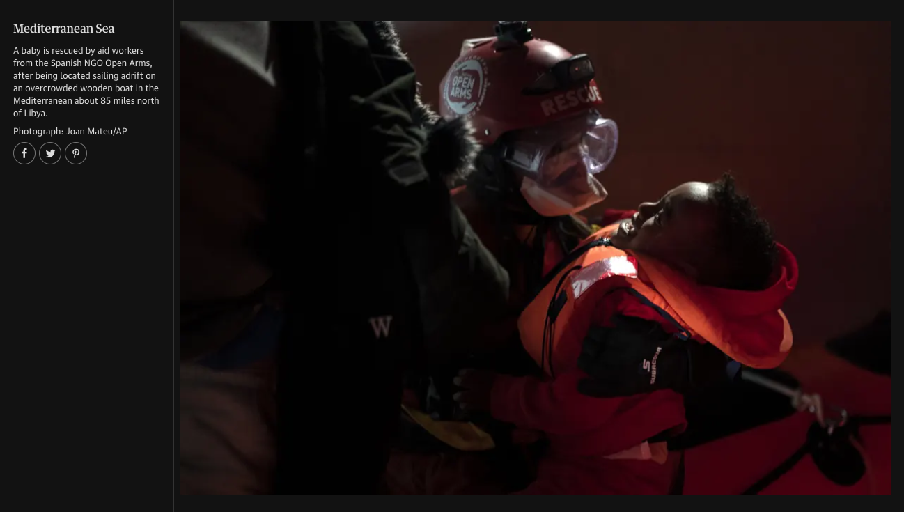 A rescue worker in protective gear helps a young boy during a rescue operation at night, with the boy lying on a rescue stretcher.