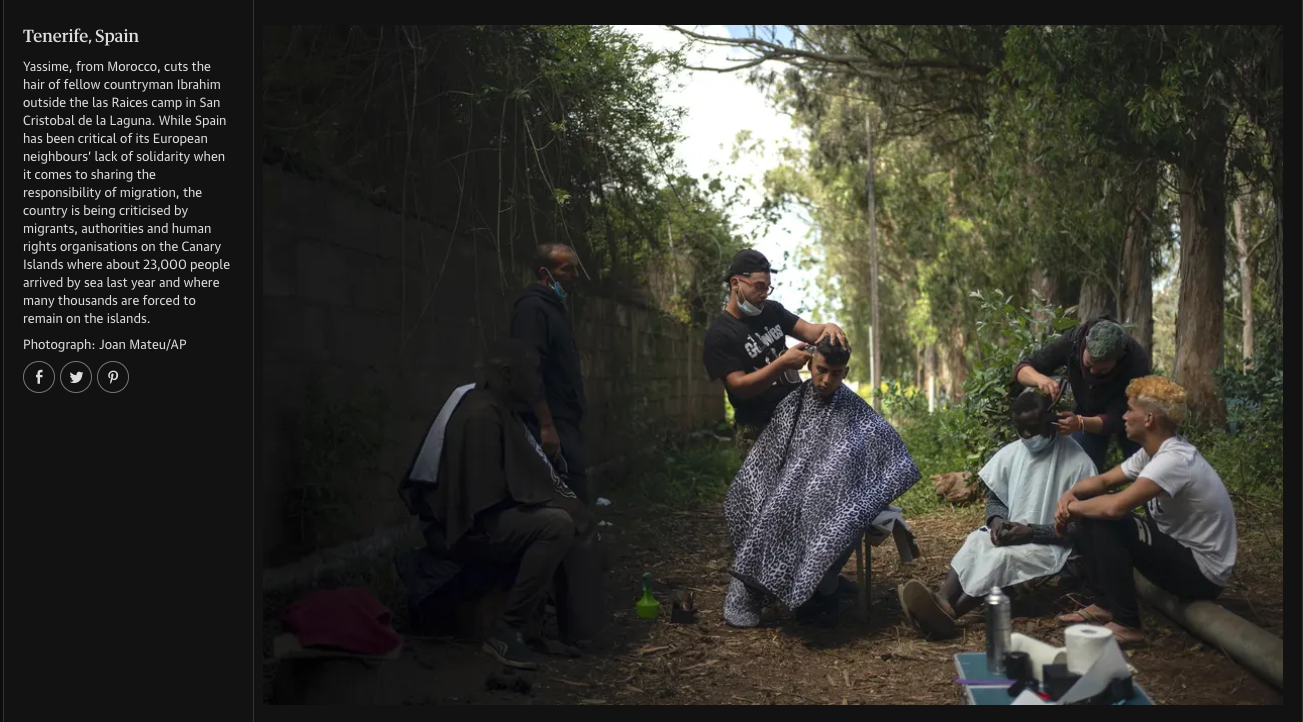Group of people getting hair cut outdoors in a shaded area surrounded by trees.