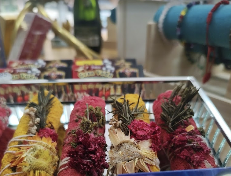 varios pequeños paquetes con hierbas y flores secas envueltas en telas de colores en una caja de exhibición