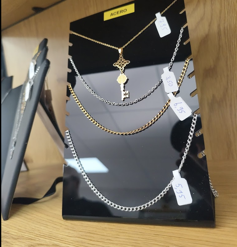 Conjunto de collares de diferentes tamaños y colores en exhibición, algunos con etiquetas de precio, en una bandeja negra sobre una mesa de madera.