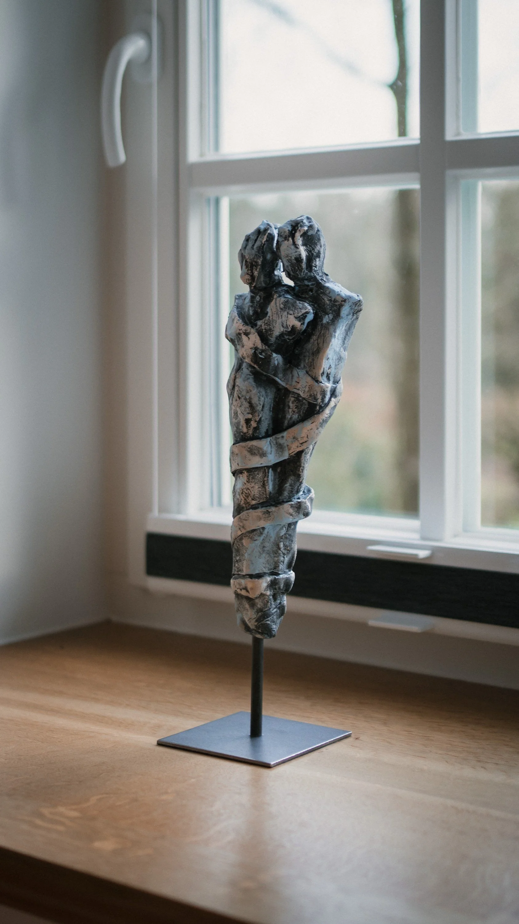 Skulptur eines Paares in einer innigen Umarmung auf einem Fensterbrett