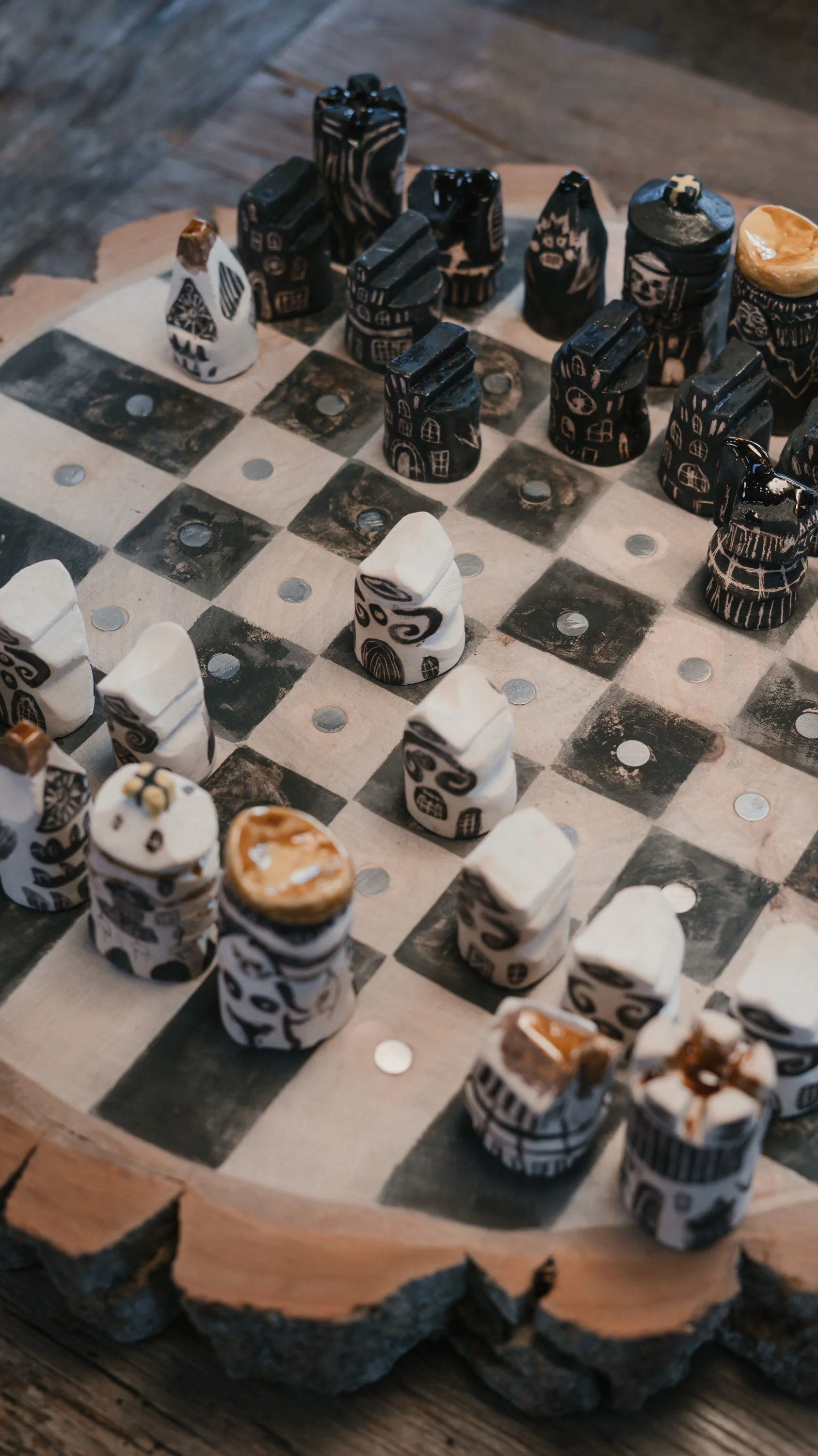 Schachspiel mit Figuren auf einem Schachbrett, das auf einem Holztisch liegt, mit einem natürlichen Holzrand.