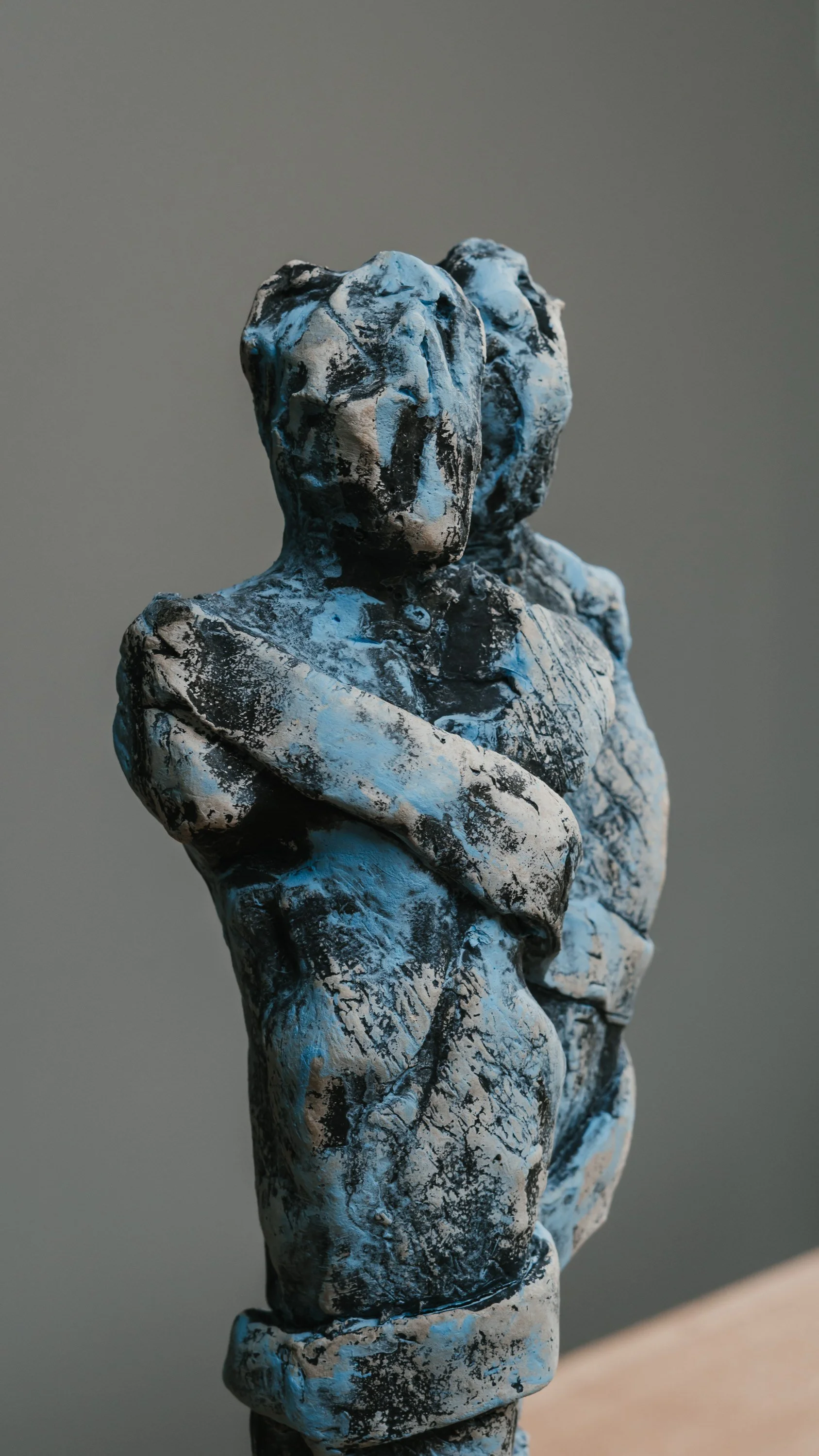 Skulptur von zwei Figuren mit verschränkten Armen, aus schwarzem, weißem und blauem Material.