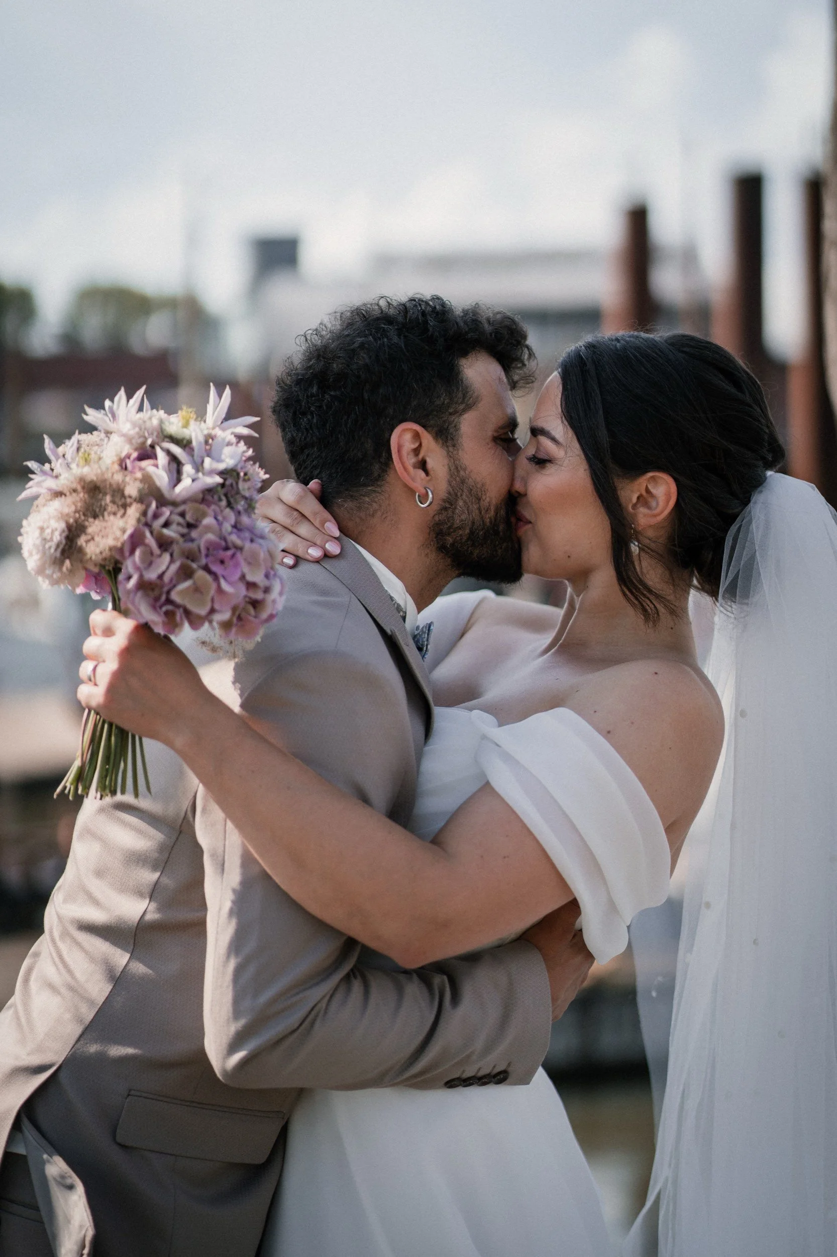 Ein Paar bei ihrer Hochzeit, umarmt sich und küsst sich leidenschaftlich im Freien.