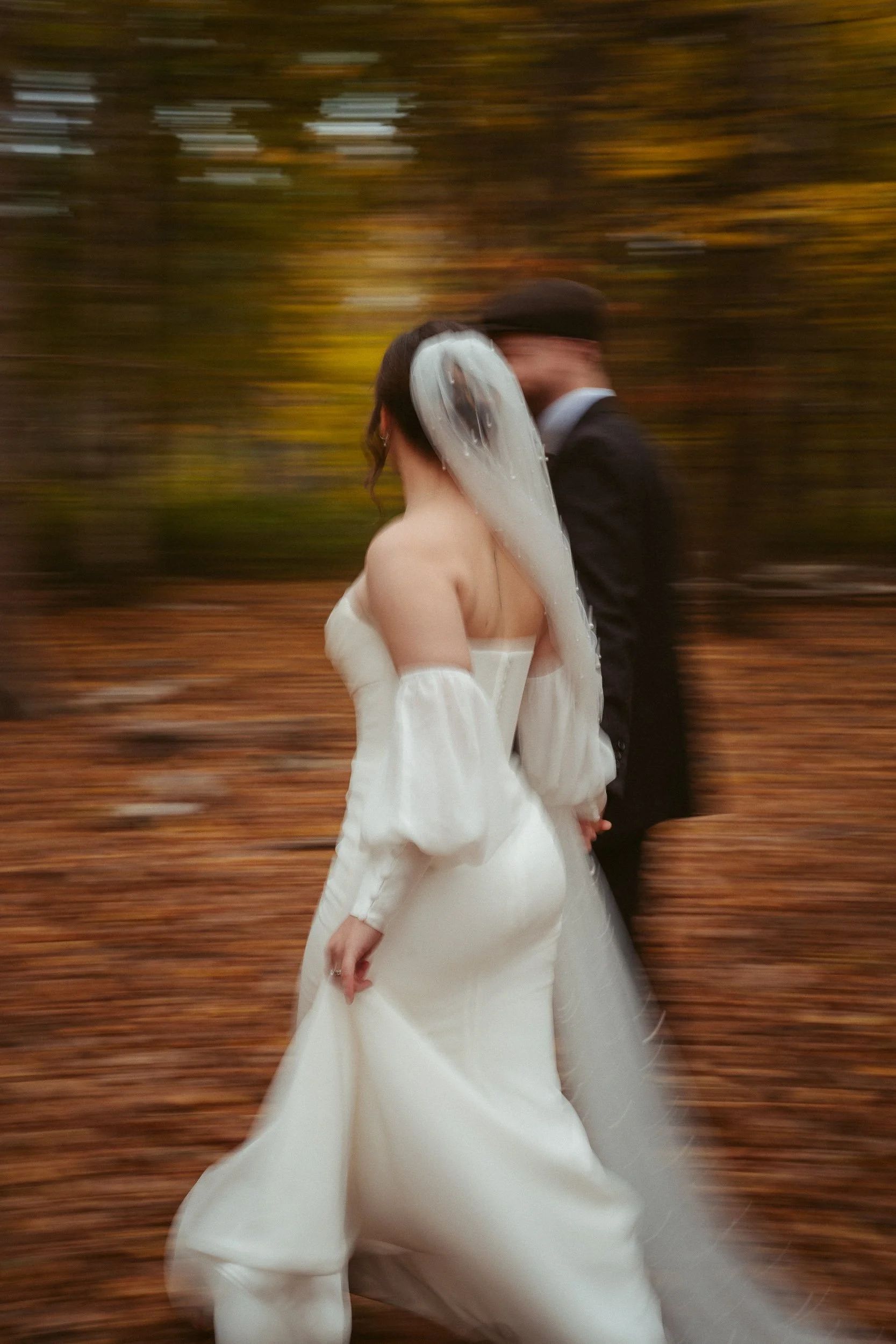 Braut und Bräutigam gehen im Herbstwald, die Bewegung ist verschwommen.