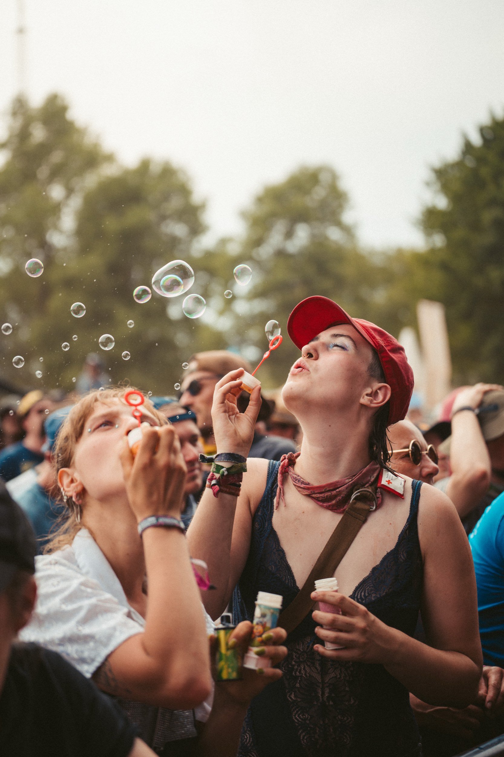 Eine Gruppe von Menschen, die bei einem Festival im Freien feiern, Blasen pusten und die Sonne scheint.