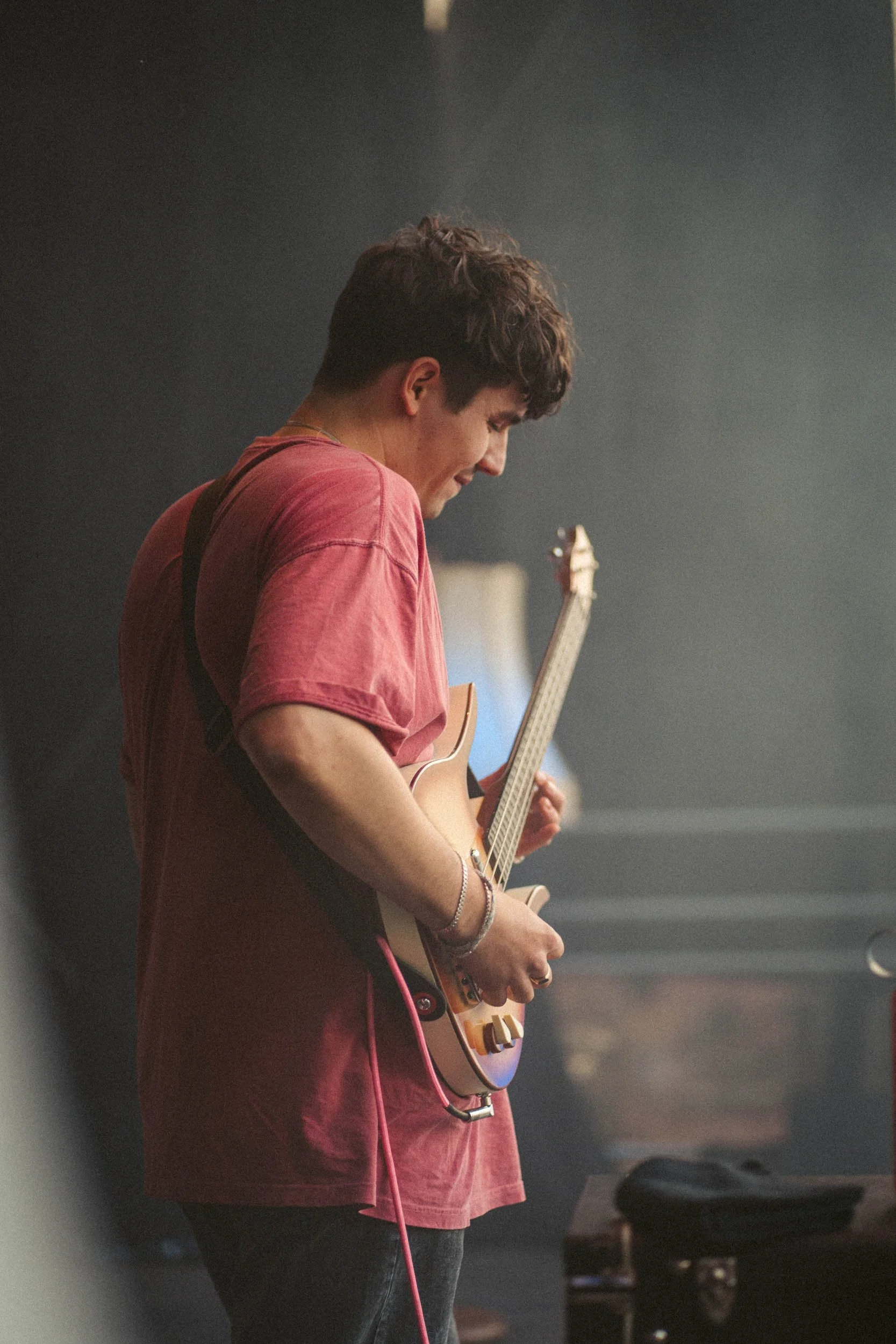 Junge spielt Gitarre in einem dunklen Raum.