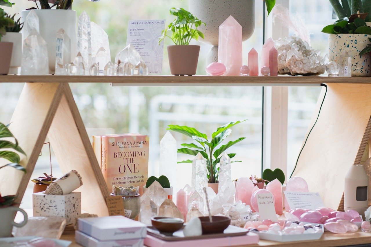 Kristalle und Mineralien im Schaufenster arrangiert, kombiniert mit Pflanzen und Büchern, ruhige Präsentation im Prana Station Store Hamburg.