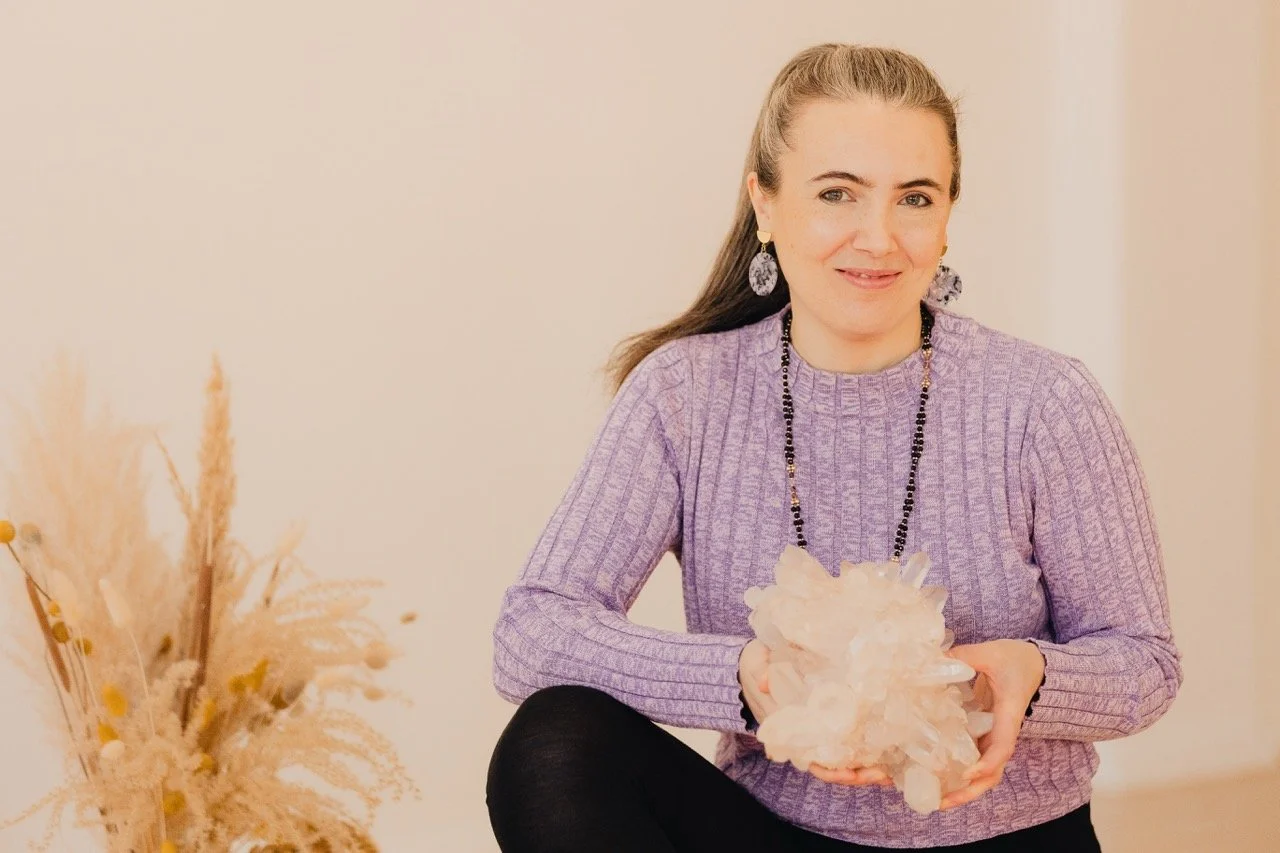 Hanna Lipp hält einen großen Bergkristall in den Händen, ruhiges Portrait in hellem Raum, Verbindung von Achtsamkeit, Präsenz und Spiritualität in der Prana Station Hamburg.