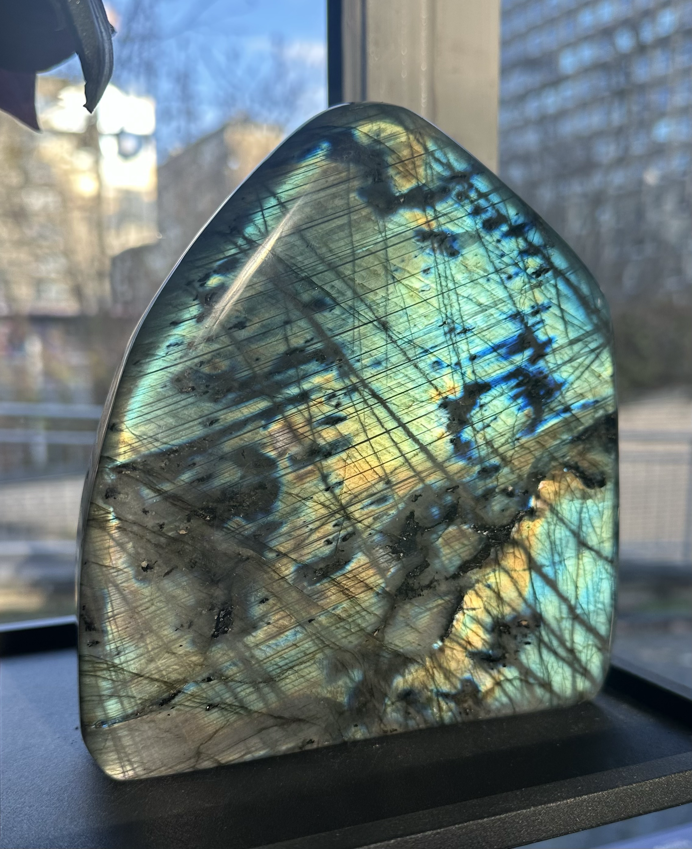 Polierter Labradorit mit schimmernden Blau- und Grüntönen im Gegenlicht, einzigartiger Edelstein mit lebendiger Oberfläche.