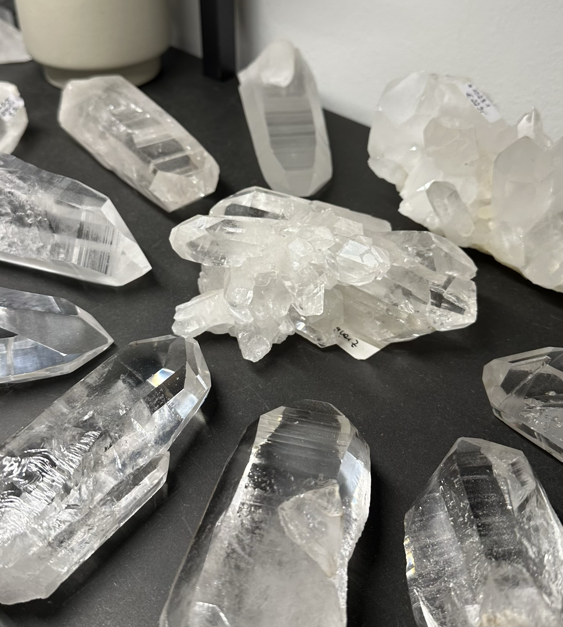 Auswahl klarer Bergkristall-Rohstücke auf dunkler Oberfläche, naturbelassene Kristalle mit kraftvoller Struktur.