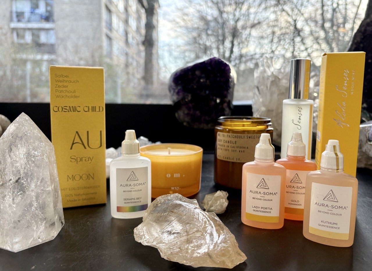 Aurasprays, Duftöle und Kerzen mit Kristallen arrangiert, spirituelle Duftprodukte für Raumharmonie und Wohlbefinden.