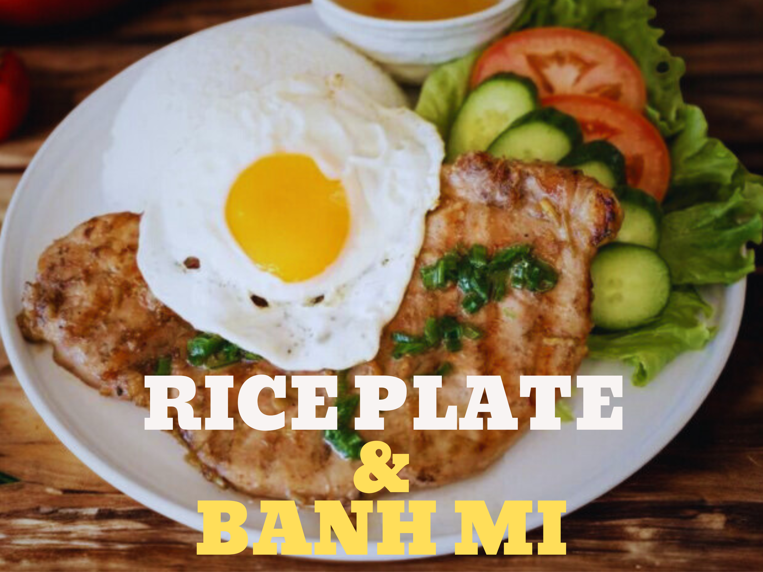 A plate with a fried egg on top of grilled chicken, served with fresh vegetables including cucumber, tomato, and lettuce. The plate has text overlay reading 'Rice Plate & Banh Mi'.