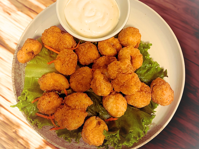 Plate of fried shrimp with lettuce and a small bowl of ranch dressing.