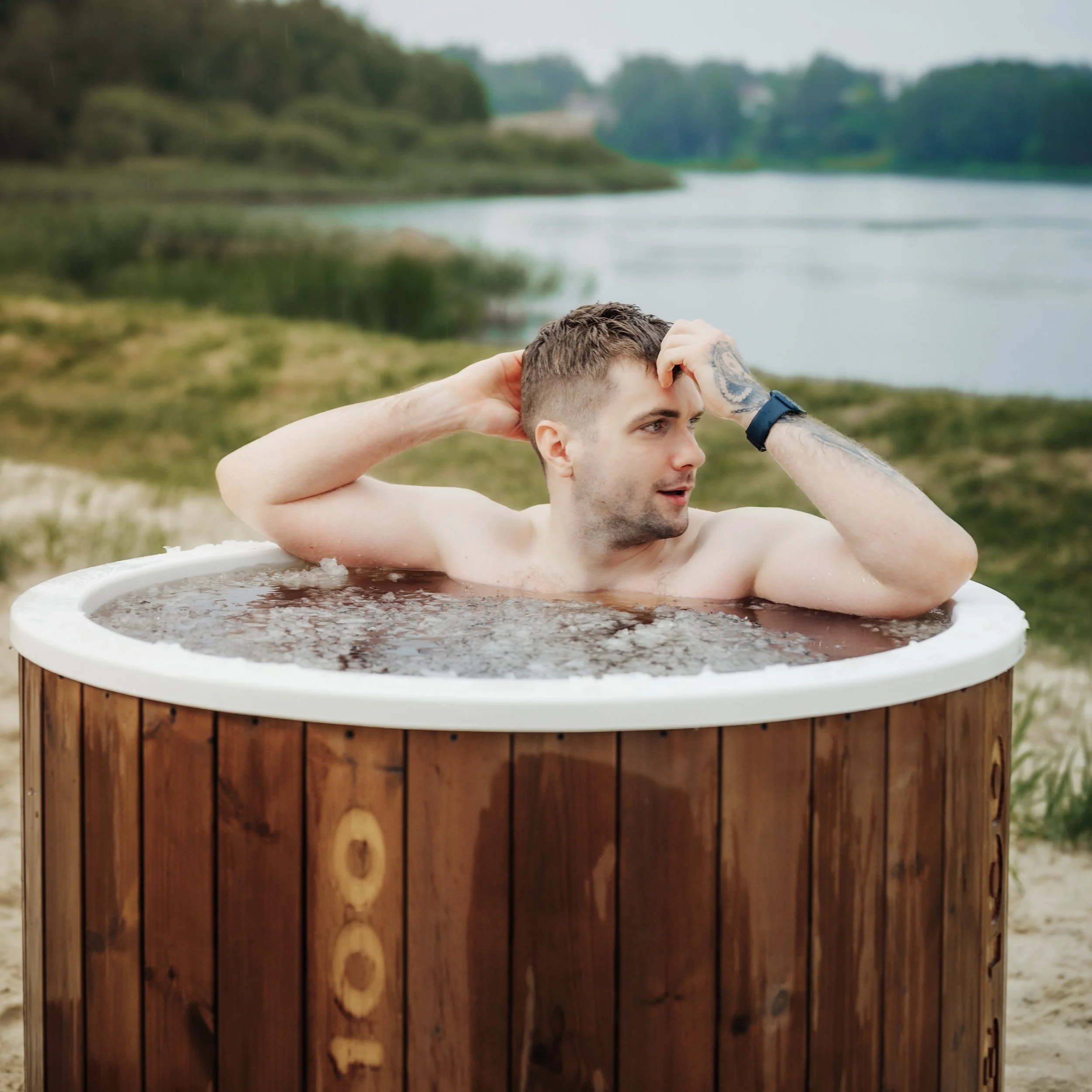 Mees lõõgastumas puidust kümblustünnis looduse keskel – külmateraapia ja heaolu hetked.