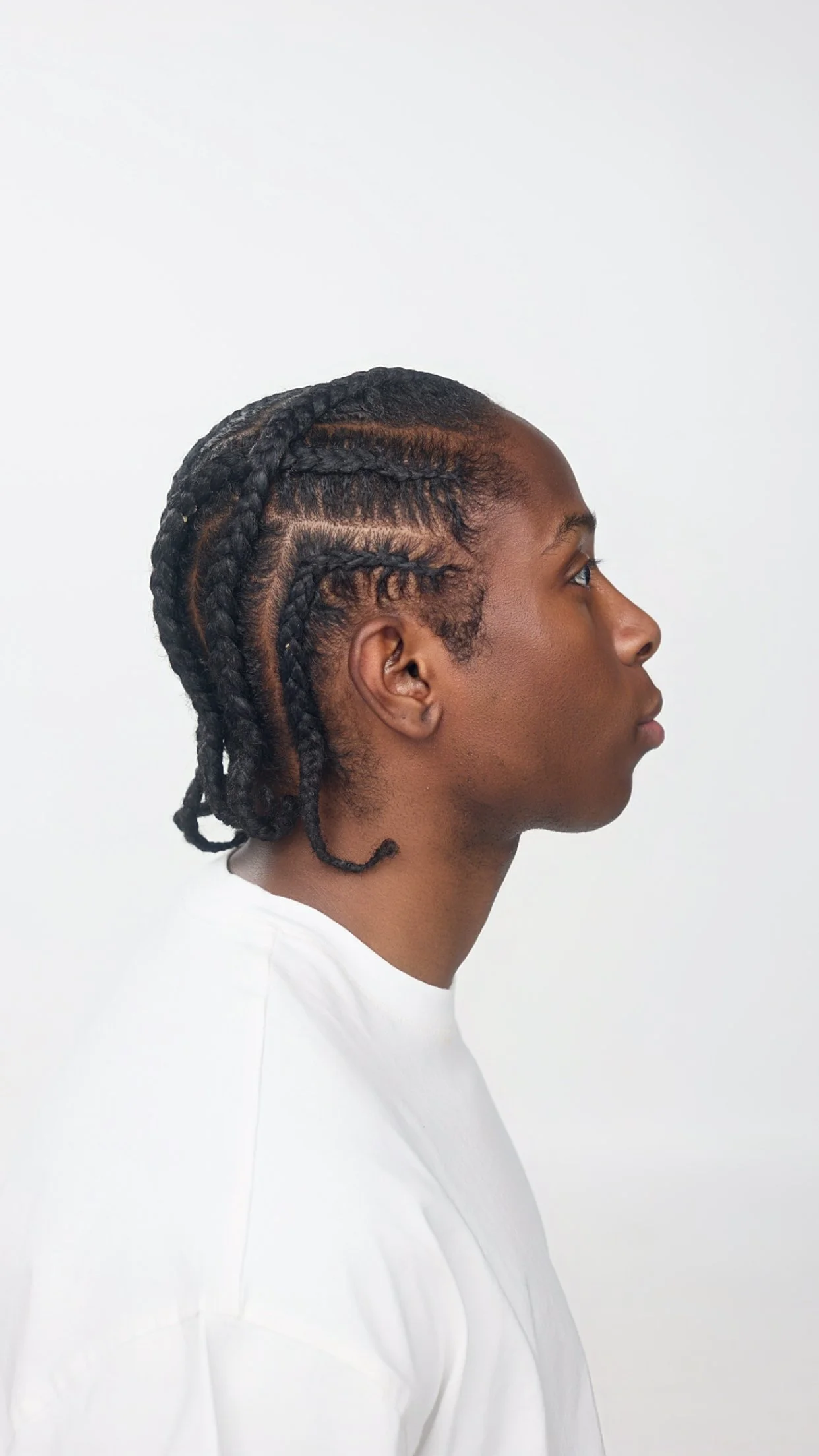Side profile of a person with neatly braided hair against a plain white background.