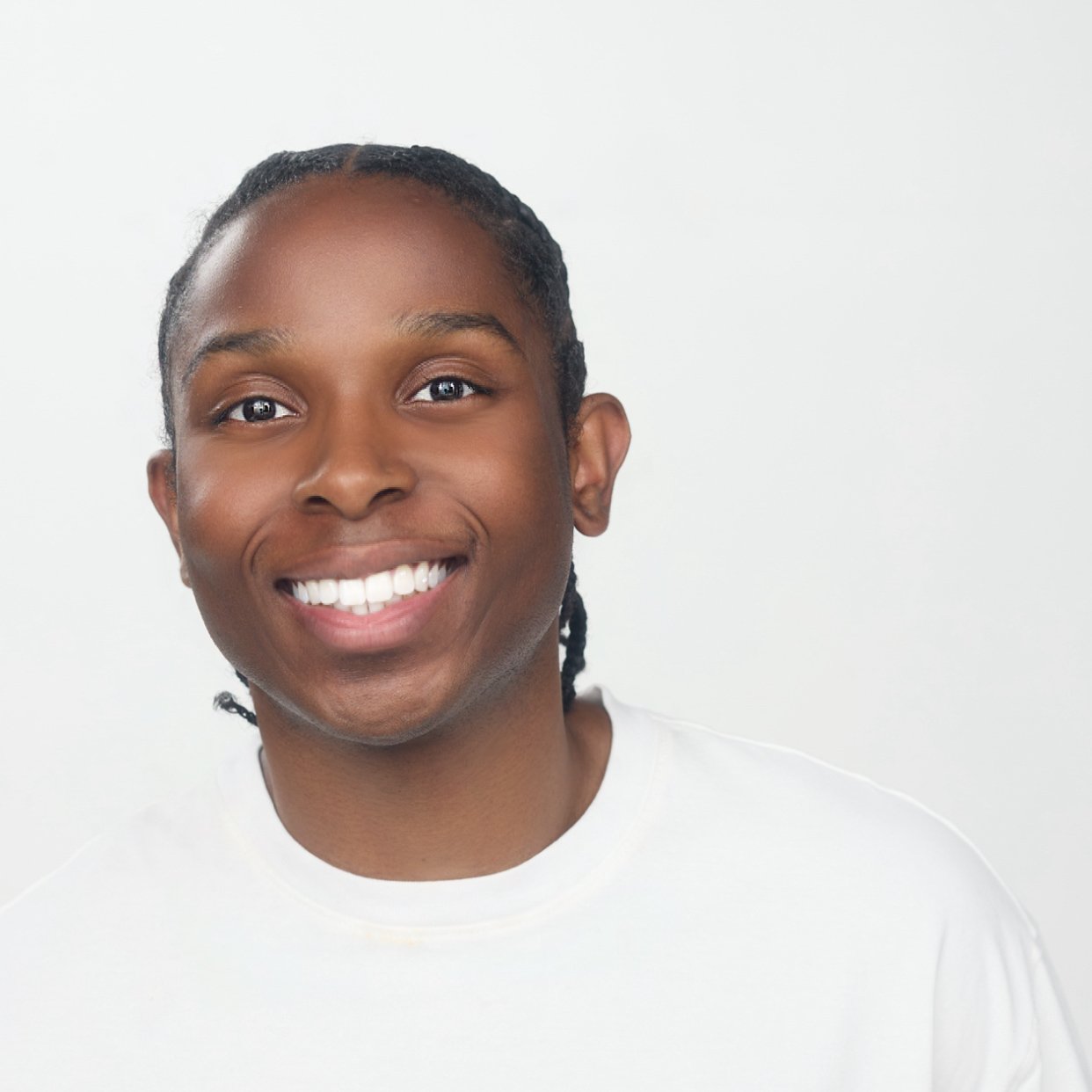 Smiling young African American man with braided hair wearing a white shirt against a plain white background.