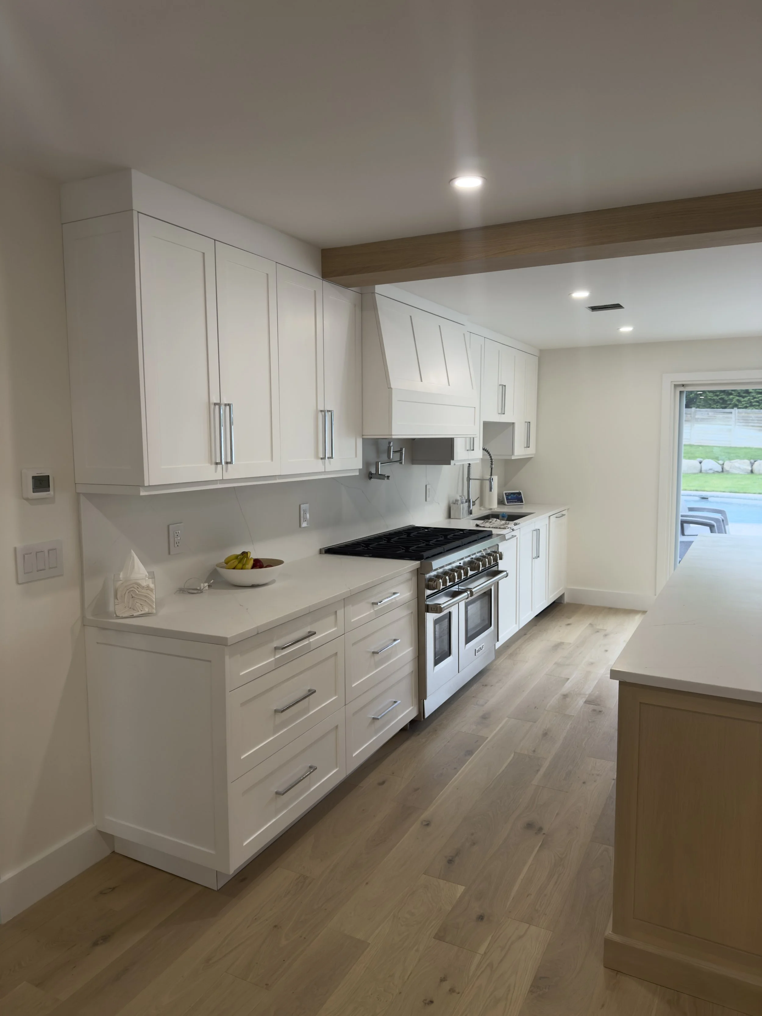 Modern kitchen with white cabinets, a stainless steel stove, and a sliding glass door to the outside.