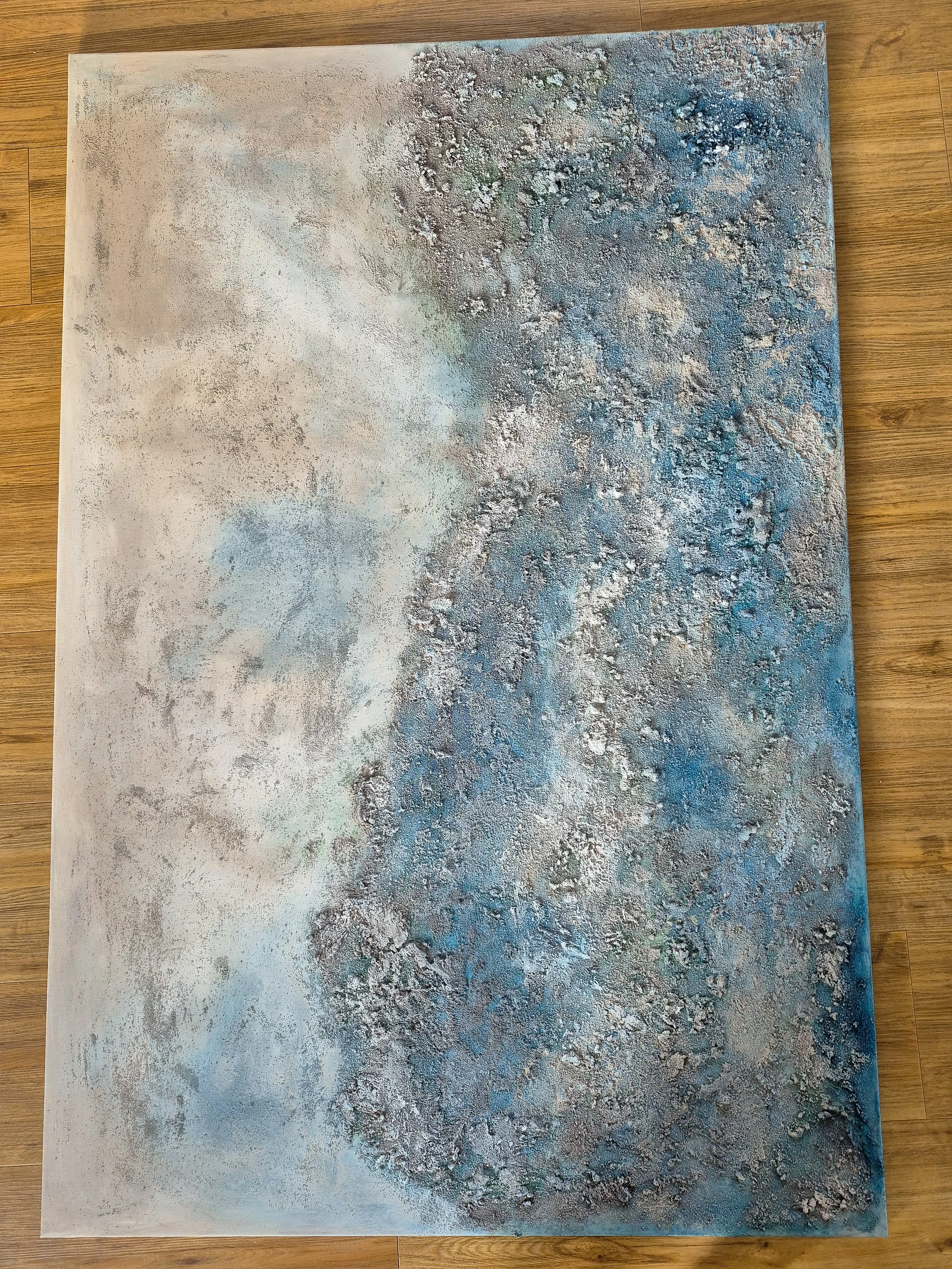 Stort abstrakt maleri i blå og sandfarvede nuancer med kraftig struktur af strandsand, 100x150 cm