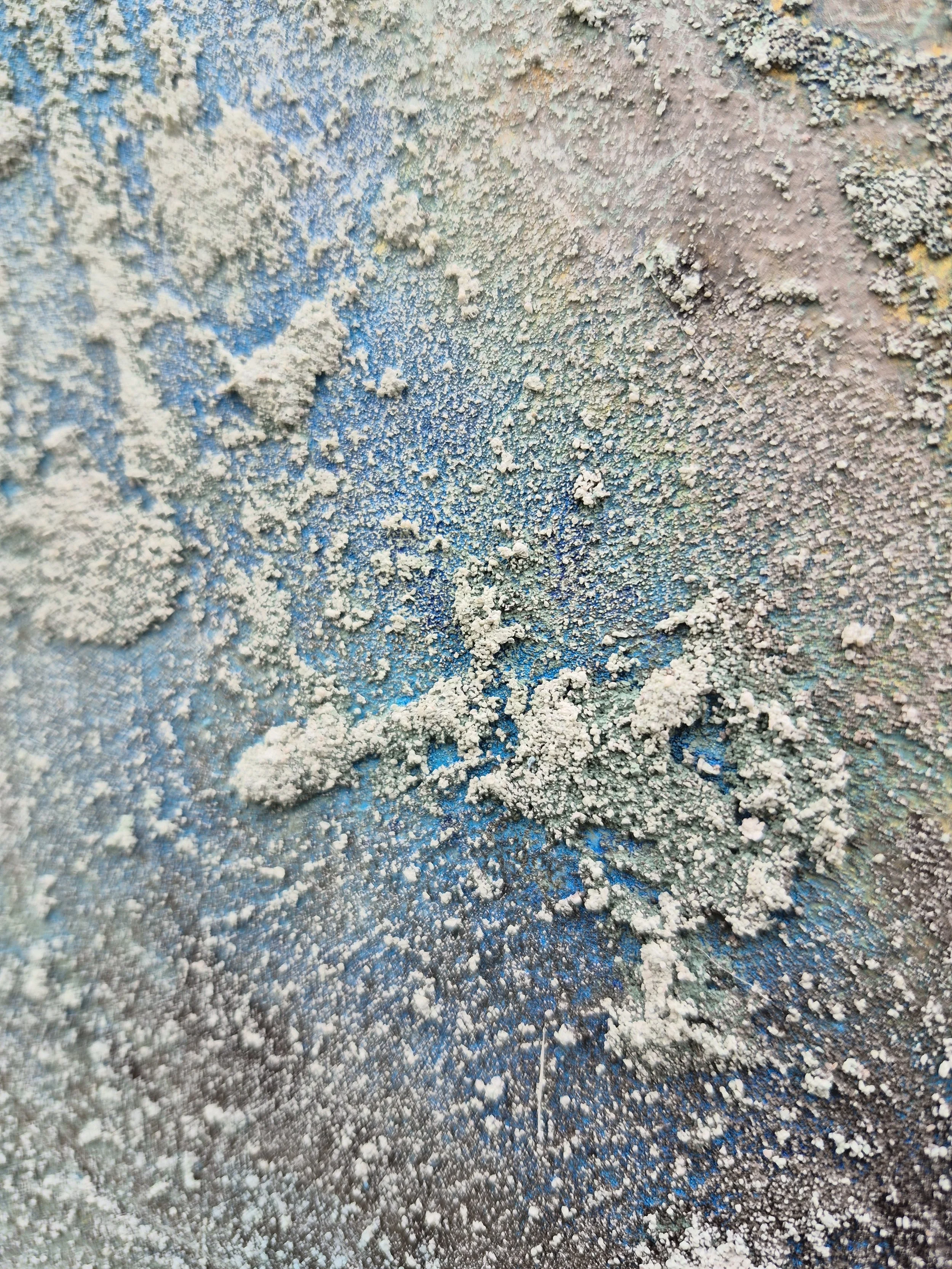 Et meget stort abstrakt maleri med kraftig struktur i hvirvlende lag af teal, søgrøn, grå, kulpigment og hvid. Maleriet hænger på en lys væg i en modern spiseplads over en skænk i lyst træ.