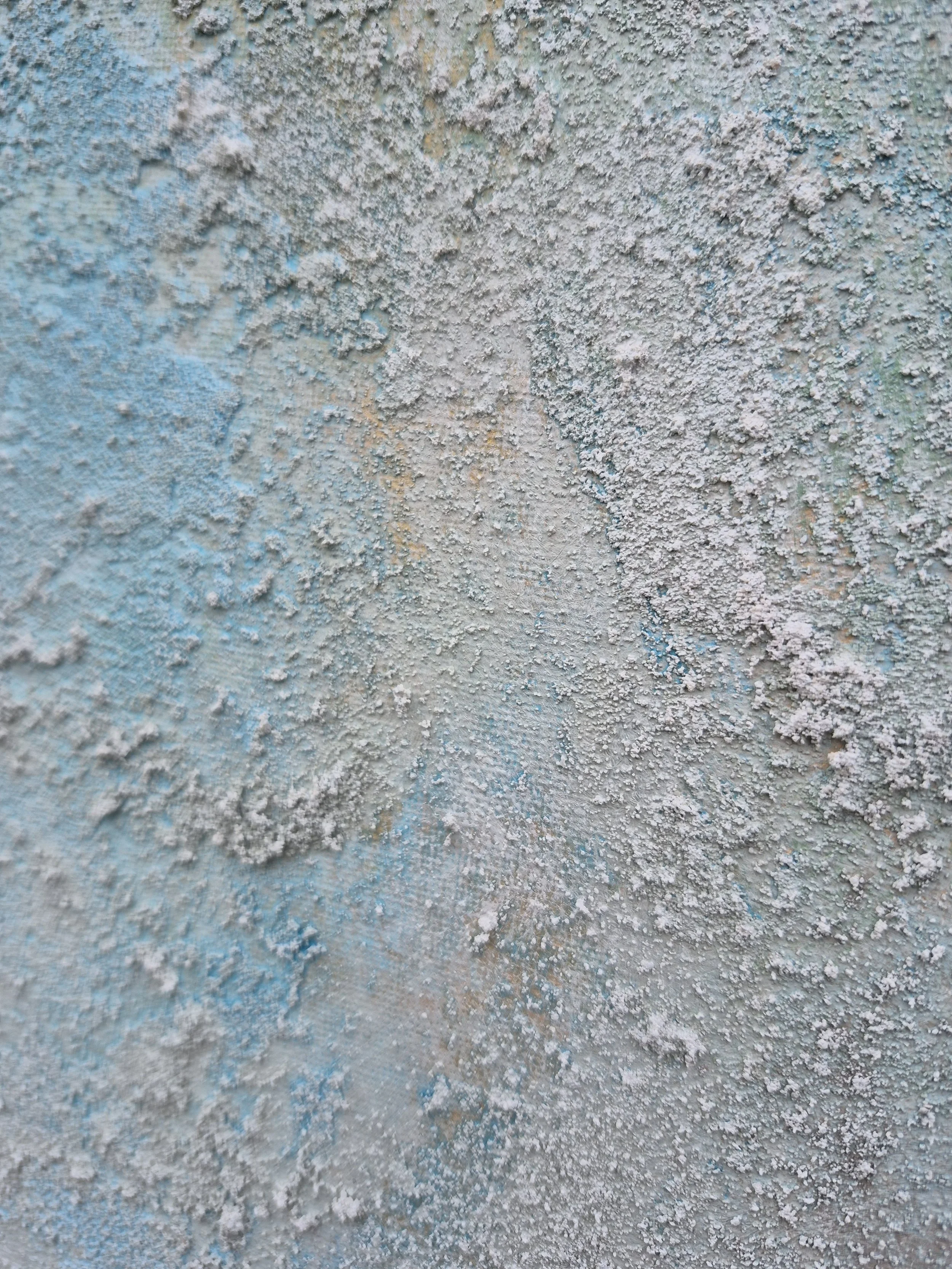 Et meget stort abstrakt maleri med kraftig struktur i hvirvlende lag af teal, søgrøn, grå, kulpigment og hvid. Maleriet hænger på en lys væg i en modern spiseplads over en skænk i lyst træ.