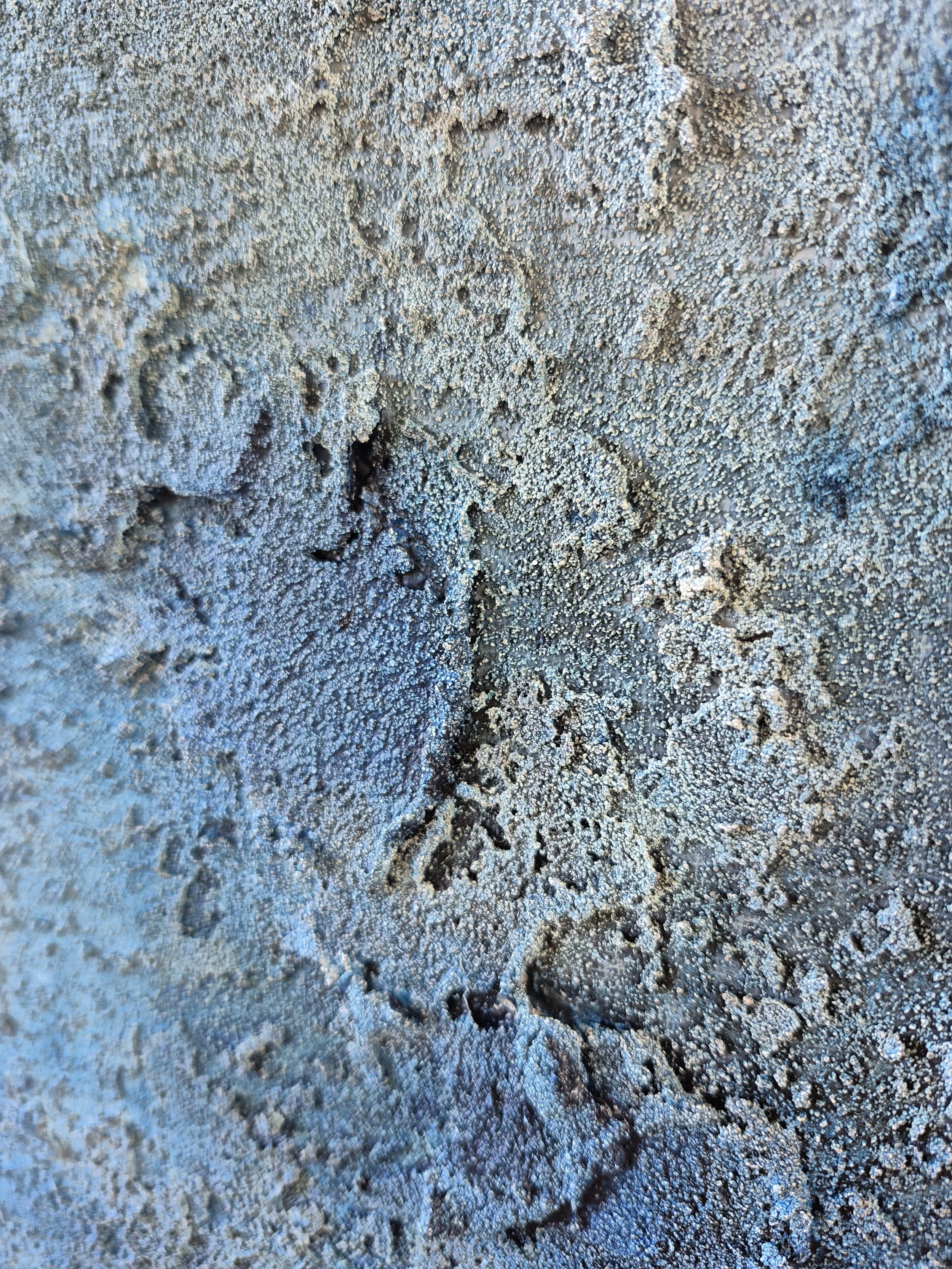 Stort abstrakt maleri med titlen 'Cosmos' udstillet på et staffeli. Maleriet har en kraftig struktur af sand og akryl i blå, grå og beige nuancer, indrammet i en lys træramme.