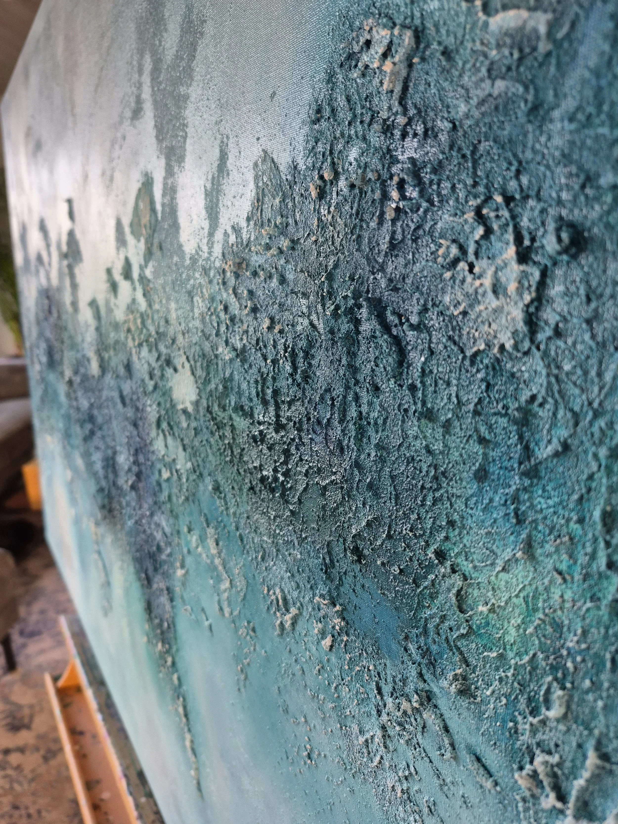 Stort blåt og turkist abstrakt maleri med titlen Continuum hængt op over en grå sofa i en moderne stue.