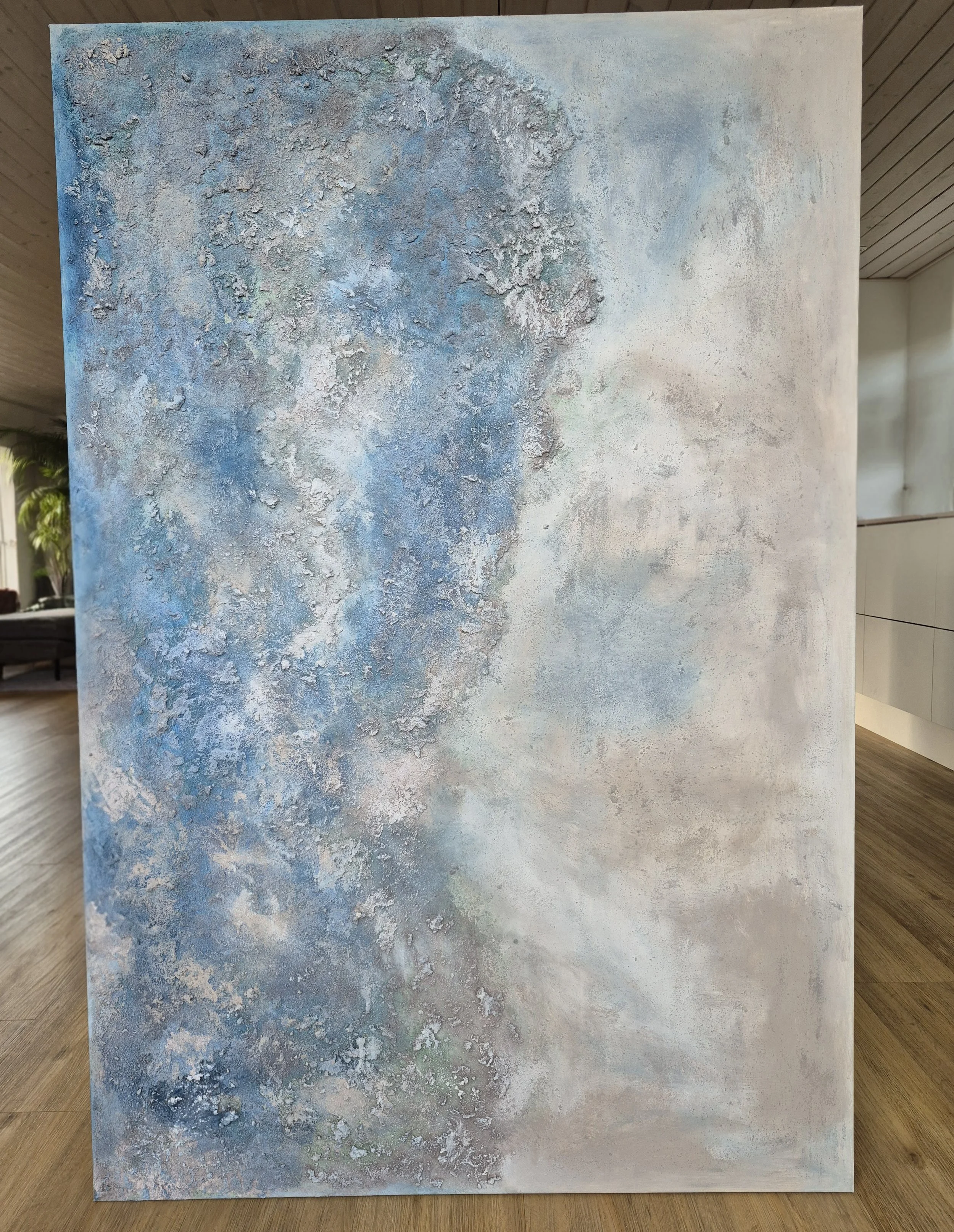 Stort abstrakt maleri i blå og sandfarvede nuancer med kraftig struktur af strandsand, 100x150 cm