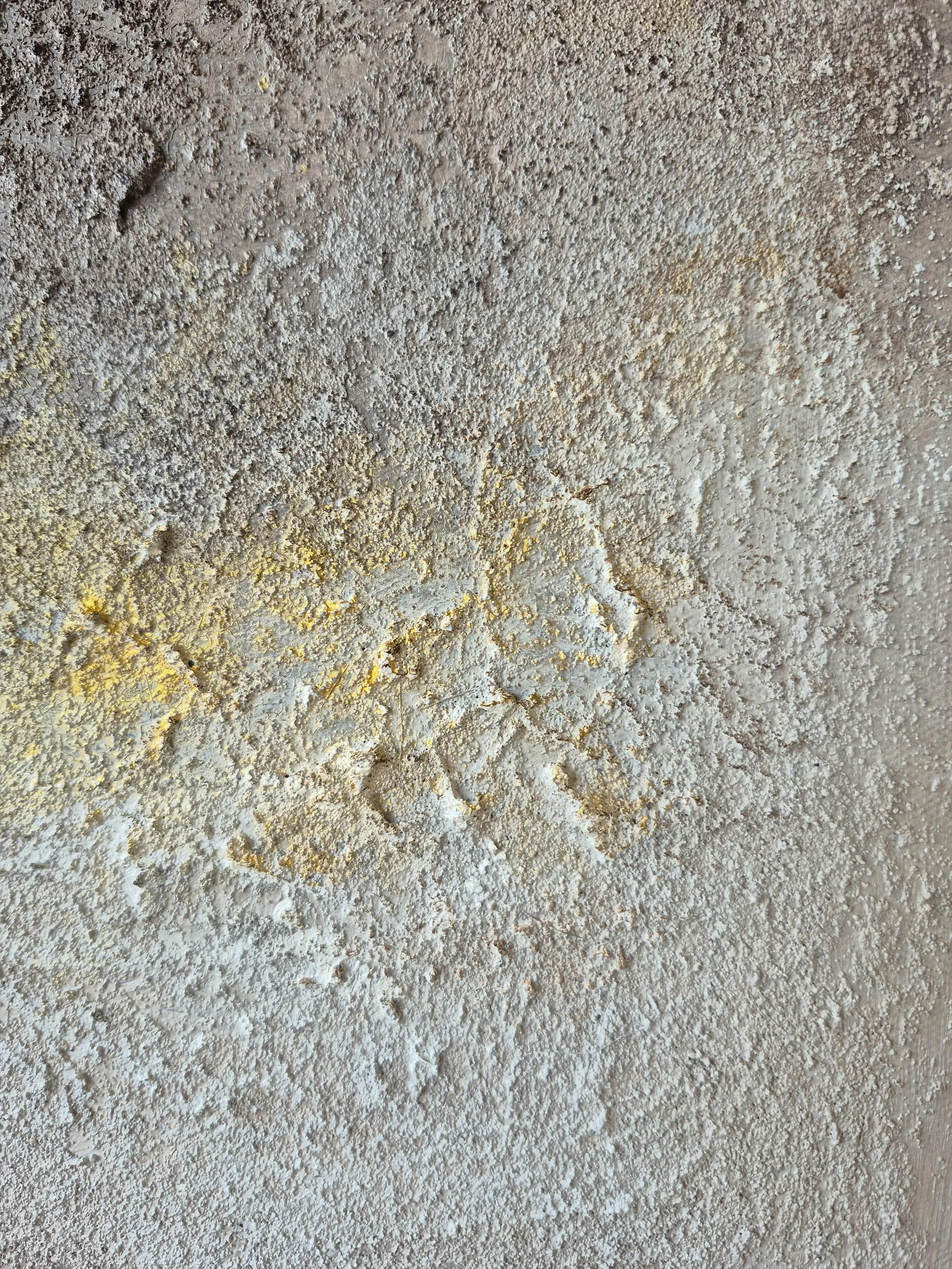 ​A square abstract textured painting featuring earth tones of grey and brown with a vibrant horizontal streak of gold leaf, hung in a bright, modern living room