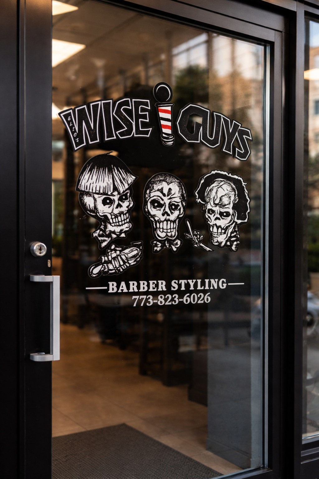 Storefront door of 'Nise Guys' barber shop with black and white skull illustrations, a barber pole logo, and the shop's phone number.