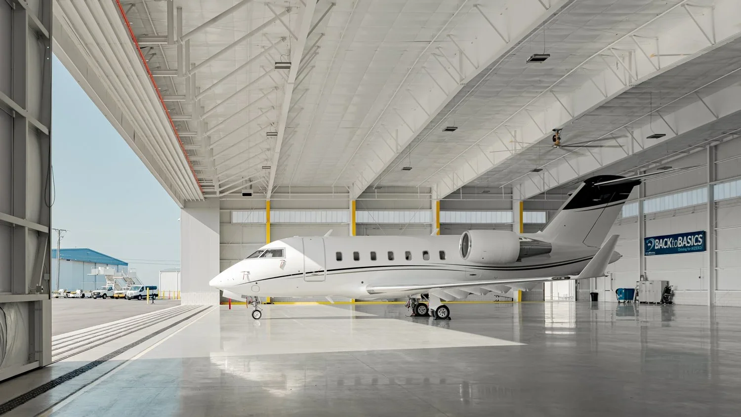 A private jet inside a spacious hangar with open doors, showing no people.