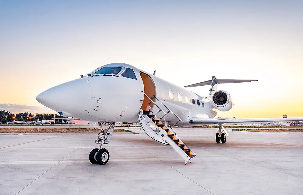 A private jet parked on the tarmac at sunset.