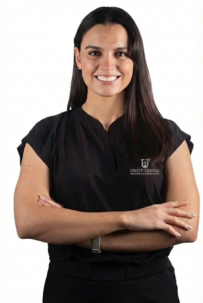 A young man sitting on a beige bench against a plain wall, wearing a gray polo shirt and light-colored pants, with a neutral expression.