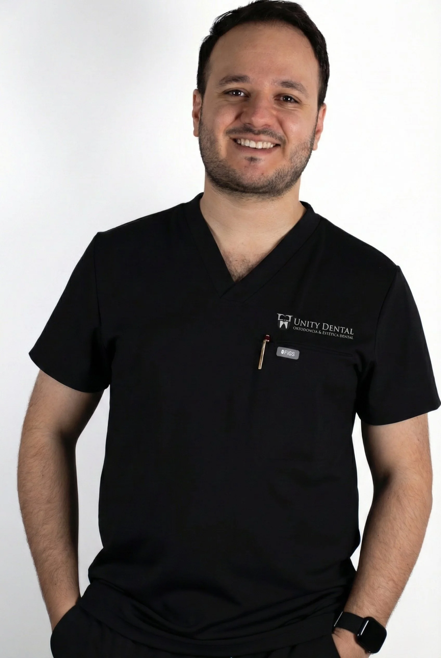 A woman with short blonde hair in a sleeveless rust-colored top and beige pants sitting on a bench, writing in a notebook with a black pen, next to a modern abstract painting and a potted plant, with sunlight casting shadows on the wall.