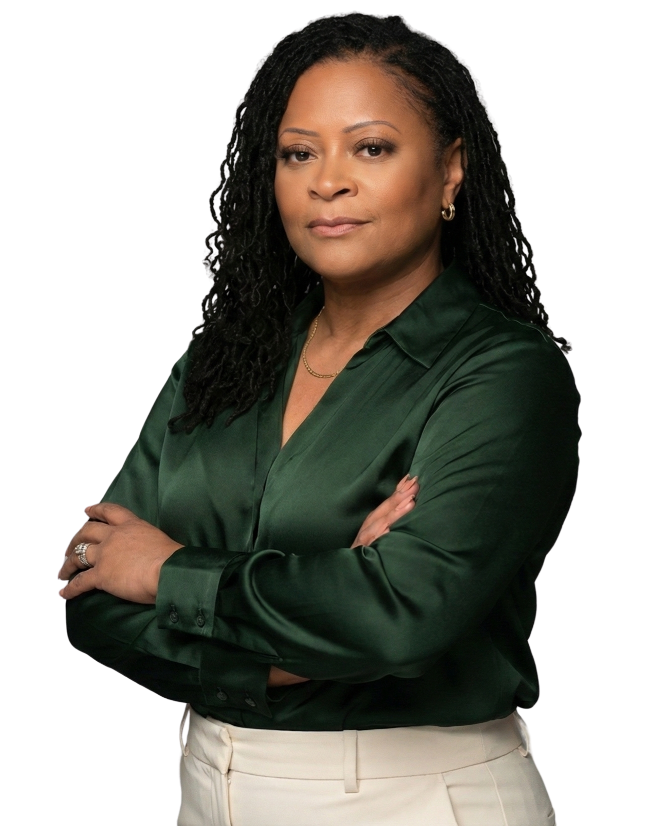 A woman with curly black hair wearing a dark green satin blouse with her arms crossed, posing confidently.