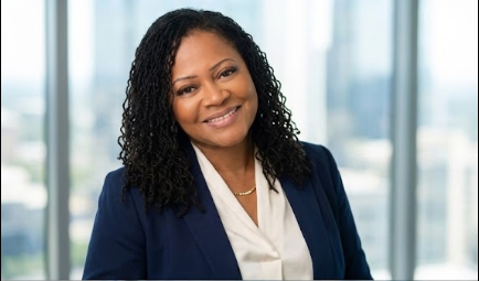 Professional woman with curly hair smiling in an office setting.